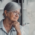 Concerned elderly woman looking out window
