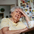 Portrait of worried senior woman sitting in kitchen. 