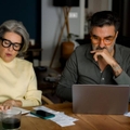 Mature couple managing finances and planning household budget at kitchen table