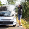 An anxious man near a broken car on the road