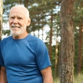 Smiling older man leaning against a tree