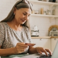 Happy senior woman making online payments of bill using laptop