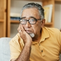 Older man looking worried resting his face on his hand