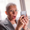 Older woman shocked looking at phone screen