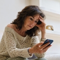 Concerned mature woman on couch looking at phone
