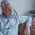 Older man sitting on couch looking distressed