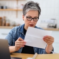 Shocked mature woman holding letter