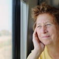 Woman in her late 70s looking through the window