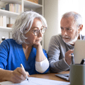 Boomer couple looking at emergency fund on laptop