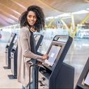 woman using check in machine at airport to avoid checked bag fees