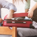 couple stuffing suitcase to avoid baggage fees
