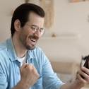 Overjoyed man wearing glasses holding smartphone