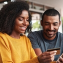 man looking at his girlfriend shopping online in cafe