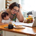 Woman holding baby and looking at computer