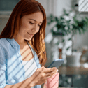 Smiling woman looking at her phone and holding a mug