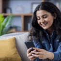 Woman sitting on couch scrolling on cell phone