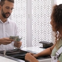 Bank teller counts cash for customer waiting at window