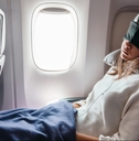 Woman sleeping on airplane with eye mask on