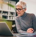 retired woman working at laptop on side hustle