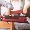 couple stuffing suitcase to avoid baggage fees
