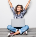 woman with laptop arms in air celebrating