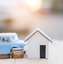 Coins next to a miniature house and car