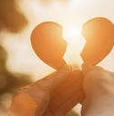 hands holding broken heart pieces in the sun 