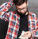 confused man standing over chalkboard while holding money