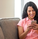 smiling Hispanic woman using her phone at home