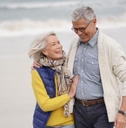 happy senior couple walking together on the beach