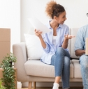 Couple sitting on couch next to moving boxes