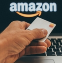 man holding a credit card in front of Amazon website