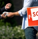 People shaking hands by &#x27;sold&#x27; house sign