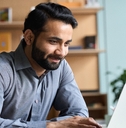 Smiling indian business man working on laptop 