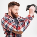 young man in plaid shirt looking inside his empty wallet