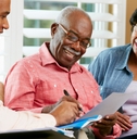 elderly man signing a document