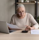 a woman using a calculator while holding a paycheck page