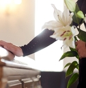 woman with lily flowers and coffin at funeral