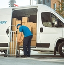 courier takes out cardboard box package from opened delivery van 