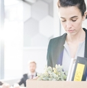 woman holding box of personal belongings leaving office