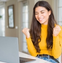 Young woman using computer laptop very happy and excited doing winner gesture