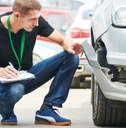 Male claims adjuster looking at damaged car