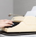 woman&#x27;s hand presses a finger on the buttons of an old typewriter