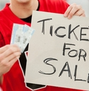 A sports fan holds two tickets and a sign that says &quot;Tickets for Sale.&quot;