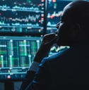 adult man looking at several screens with charts on them