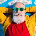 adult man with white beard lying on top of money