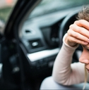 woman in the damaged car after a car accident making a phone call