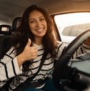 happy woman driving a car with her thumb up