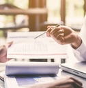 Two men looking at paper financial reports on a table