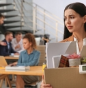 dismissed young woman carrying box with stuff in office